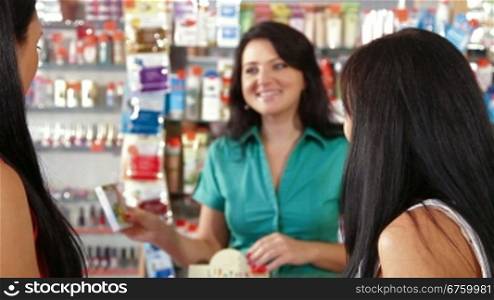 Young women shopping in cosmetics store, shop assistant offers goods for body care