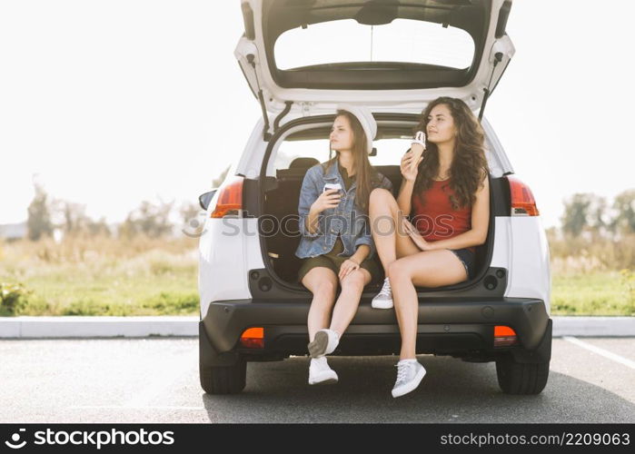 young women sitting car trunk