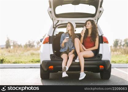 young women sitting car trunk