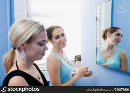 Young women standing in front of mirror