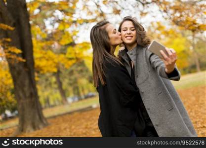 Young women taking selfie with mobile phone in the autumn forest