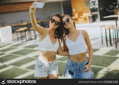 Young women taking selfie with mobile phone outdoor at hot summer day