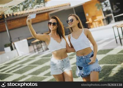 Young women taking selfie with mobile phone outdoor at hot summer day