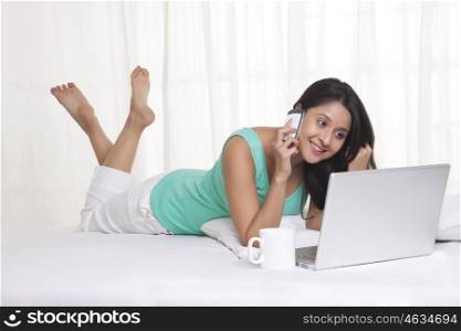 Young WOMEN using laptop while talking on mobile phone