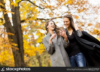 Young women with mobile phone in the autumn park