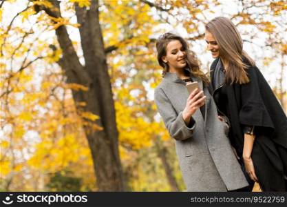 Young women with mobile phone in the autumn park