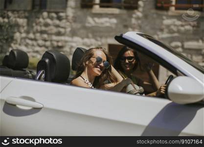 Young women with sunglasses in  convertible top automobile on bright sunny day near sea