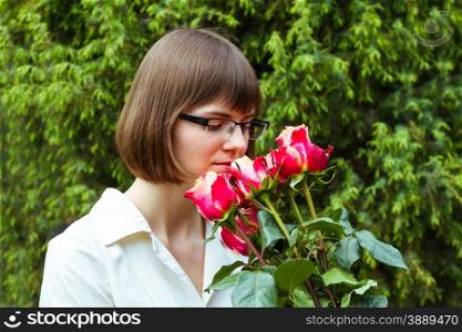 young wooman with scarlet roses on coniferous background