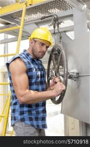 Young worker fixing industrial valve with wrench
