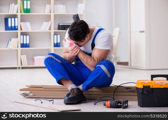 Young worker working on floor laminate tiles