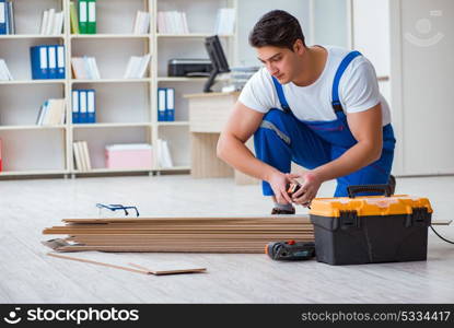 Young worker working on floor laminate tiles