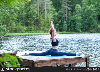 Young yogi  girl  practicing yoga, stretching in Monkey God exercise, Splits, Hanumanasana pose on the lake. The concept of appeasement,  healthy lifestyle. 
