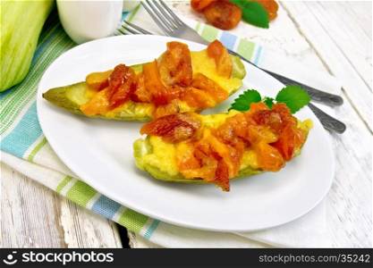 Young zucchini baked in a flavored sauce with dried apricot, cream and cheese in a white plate on a towel on the background of wooden boards