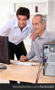 Younger and older men looking at a computer