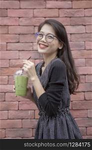 younger asian woman and glasses of ice green tea beverage in hand