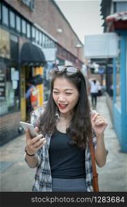 younger asian woman looking to read message on smart phone and with happiness emotion