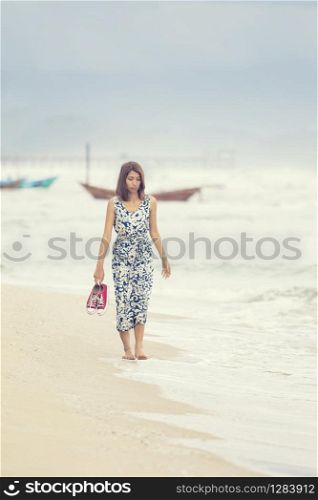 younger asian woman walking on sea beach