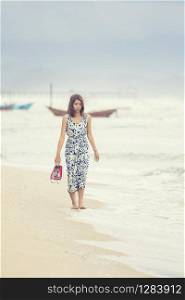 younger asian woman walking on sea beach