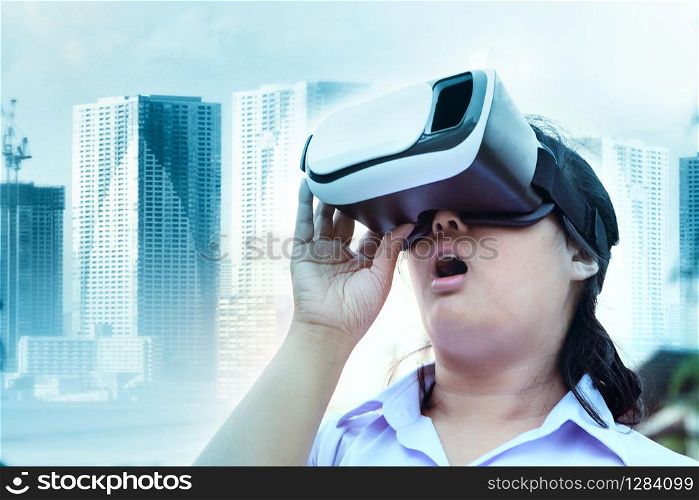 younger woman wearing virtual reality glasses with surprising face standing outdoor against modern city building background