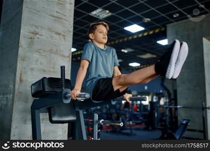 Youngster doing ABS exercise on machine in gym. Boy on fitness training in sport club, healthcare and healthy lifestyle, schoolboy on workout. Youngster doing ABS exercise on machine in gym