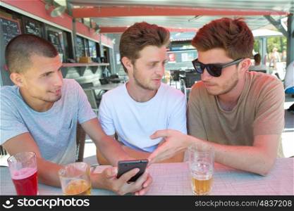 youngsters at a bar watching photos on mobile phone