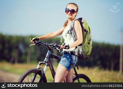 Your active lifestyle position. Young sporty girl with backpack riding bicycle along roadside