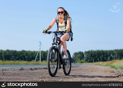 Your active lifestyle position. Young sporty girl with backpack riding bicycle along roadside