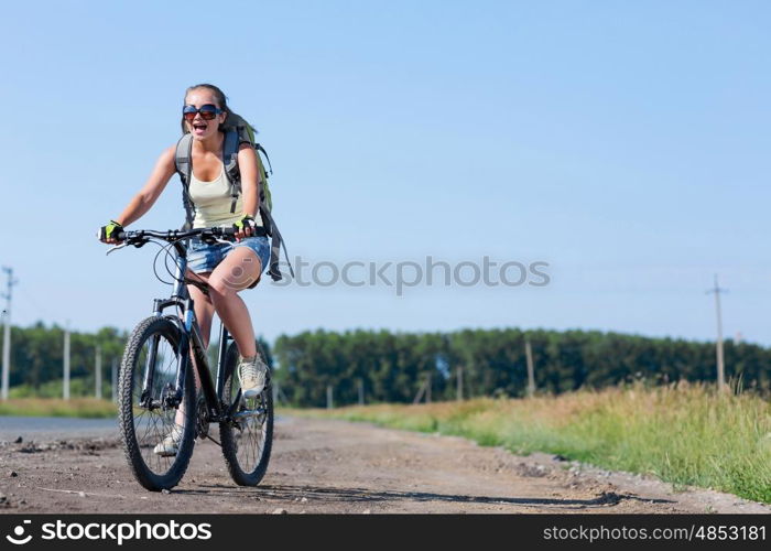 Your active lifestyle position. Young sporty girl with backpack riding bicycle along roadside