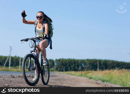 Your active lifestyle position. Young sporty girl with backpack riding bicycle along roadside