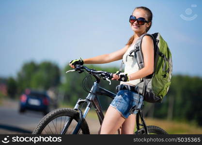 Your active lifestyle position. Young sporty girl with backpack riding bicycle along roadside