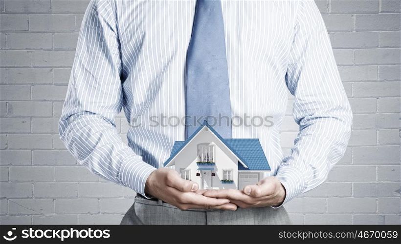 Your dream house. Close up of businessman holding house model in hands