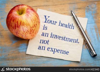 Your health is an investment, not an expense - wellness concept - handwriting on a napkin with a fresh apple