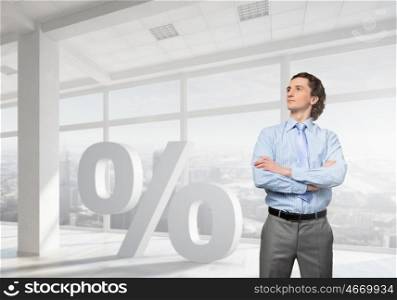 Your personal interest rate . Confident businessman standing with arms crossed on chest in modern office