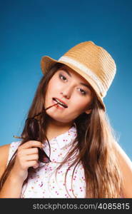 Youth and vacation concept. Happy teen girl in summer clothes and straw hat. Portrait of smiling beauty woman tourist on blue.