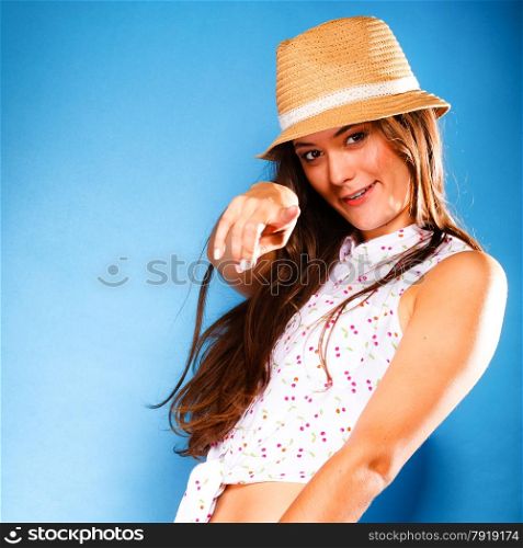 Youth and vacation concept. Happy teen girl in summer clothes and straw hat having fun. Portrait of smiling beauty woman tourist on blue.