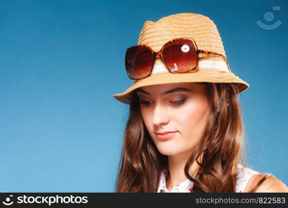 Youth and vacation concept. Lovely teen girl in summer straw hat and sunglasses. Portrait of beauty woman tourist on blue.