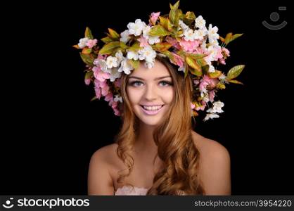 Ypung beautiful woman with a wreath of spring flowers, isolated on black