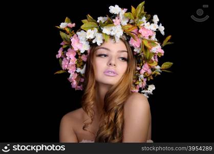 Ypung beautiful woman with a wreath of spring flowers, isolated on black