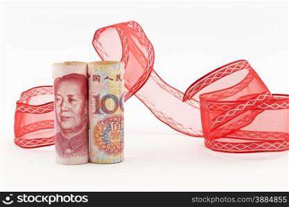 Yuan currency stands upright in front of swirl of red ribbon on white background in horizontal image.