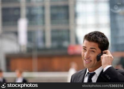 Yuppie businessman making a call outside office