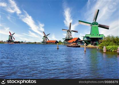 ZAANSE SCHANS, NETHERLANDS - CIRCA AUGUST 2020  Dutch windmill in green countryside close to Amsterdam, with blue sky and river water.