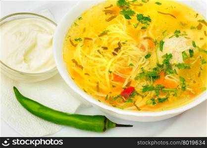 Zama, romanian and moldavian chicken soup with home-made noodles, served with green hot pepper and cream