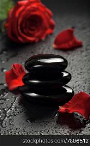zen stones and rose petals over black background