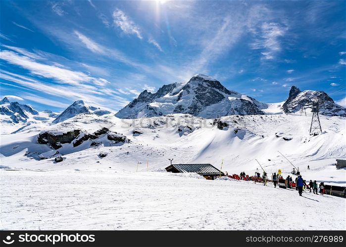ZERMATT, SWITZERLAND - MARCH 27, 2018 : Mountaineous landscape in the Alps of Switzerland with the skiers walking at the ski tracks