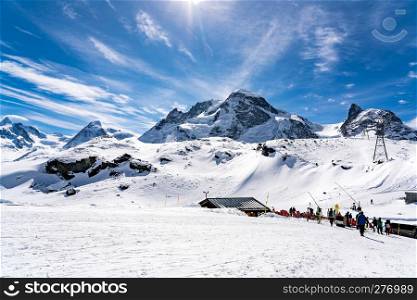 ZERMATT, SWITZERLAND - MARCH 27, 2018 : Mountaineous landscape in the Alps of Switzerland with the skiers walking at the ski tracks