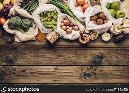 Zero waste concept. Eco bags with fruits and vegetables, glass jars with beans, lentils, pasta. Eco-friendly shopping and cooking concept, flat lay, copy space