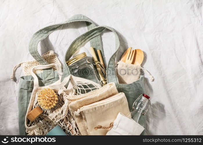 Zero waste concept. Textile eco bags, glass jars, bamboo recycled tableware on linen background with copy space for text. Eco friendly and reuse concept. Top view or flat lay