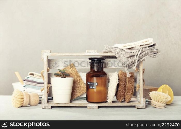 Zero waste home kitchen cleaning concept, front view of dish washing brushes, organic soap bar, kitchen towels, house plant, baking soda, lemon and eco safe all purpose cleaner in reused glass jar, blank space for a text, banner. Zero waste home kitchen cleaning concept, front view