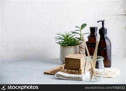 Zero waste, Recycle, Reuse, Sustainable lifestyle concept. Eco-friendly bathroom accessories: toothbrushes, reusable cotton make up removal pads, make up remover and body lotion in glass containers, natural brushes, handmade soap and house plants against white wall.