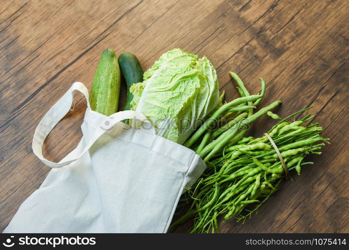 Zero waste use less plastic concept / Fresh vegetables organic in eco cotton fabric bags on wooden table - white tote canvas cloth bag from market free plastic shopping